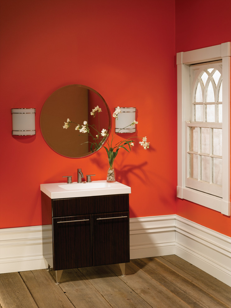 Example of a trendy light wood floor bathroom design in Raleigh with a drop-in sink, furniture-like cabinets, red walls, dark wood cabinets and solid surface countertops