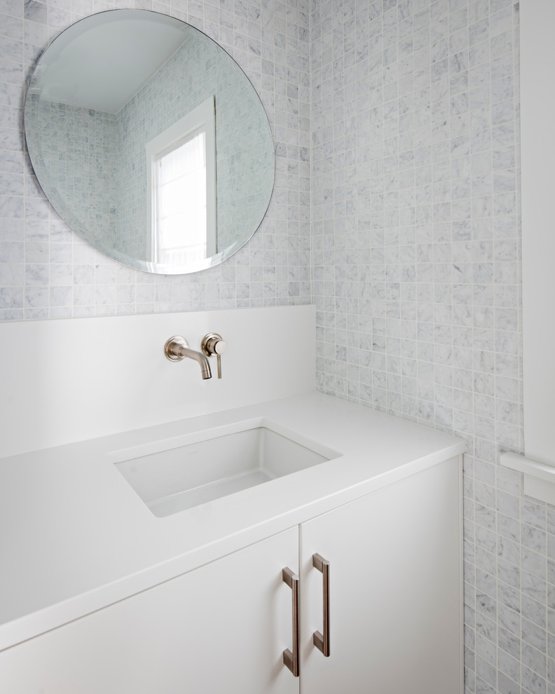 Inredning av ett modernt vit vitt toalett, med släta luckor, vita skåp, ett undermonterad handfat, bänkskiva i kvarts, blå kakel, keramikplattor och grå väggar