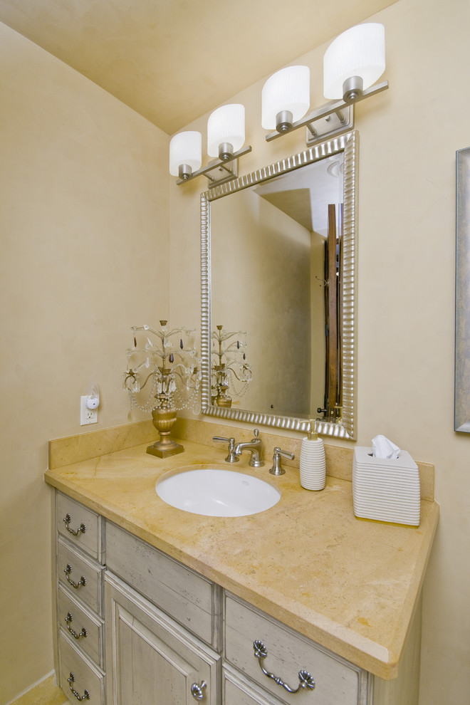 Immagine di un bagno di servizio design con lavabo sottopiano, ante con bugna sagomata e ante beige