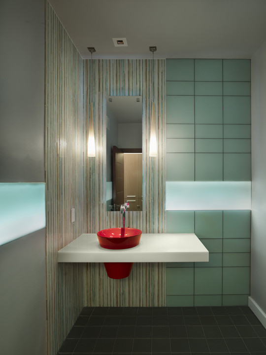 Idee per un piccolo bagno di servizio minimal con top in superficie solida, WC monopezzo, piastrelle verdi, piastrelle di vetro, pareti multicolore, pavimento in cemento e lavabo da incasso