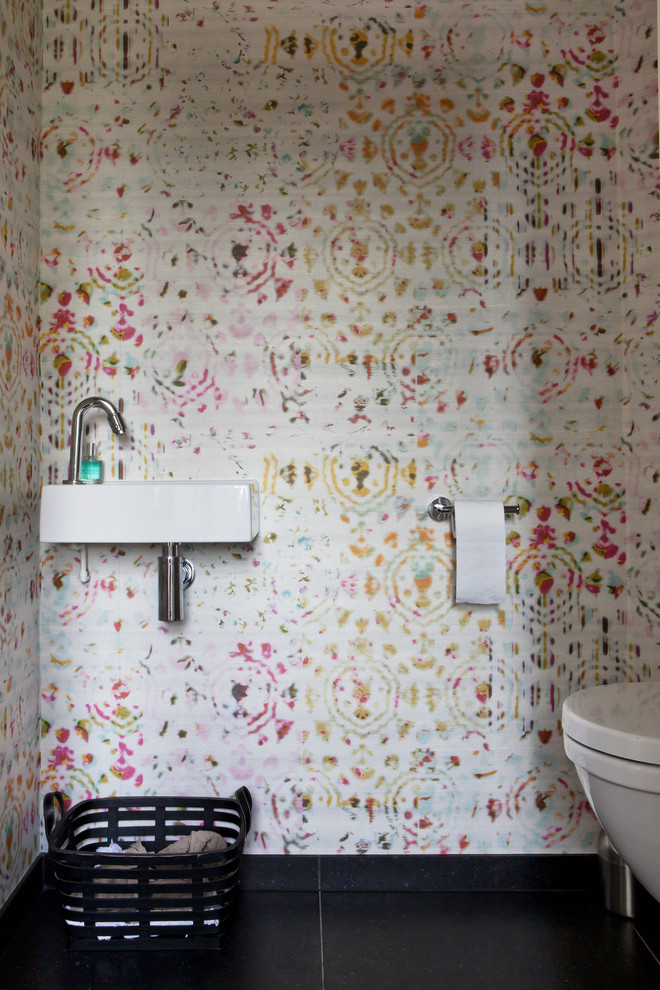 Пример оригинального дизайна: туалет в современном стиле с разноцветными стенами, подвесной раковиной и черным полом