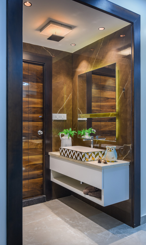 Immagine di un bagno di servizio contemporaneo di medie dimensioni con ante lisce, ante bianche, piastrelle marroni, lavabo a bacinella, pavimento grigio, top beige e mobile bagno sospeso