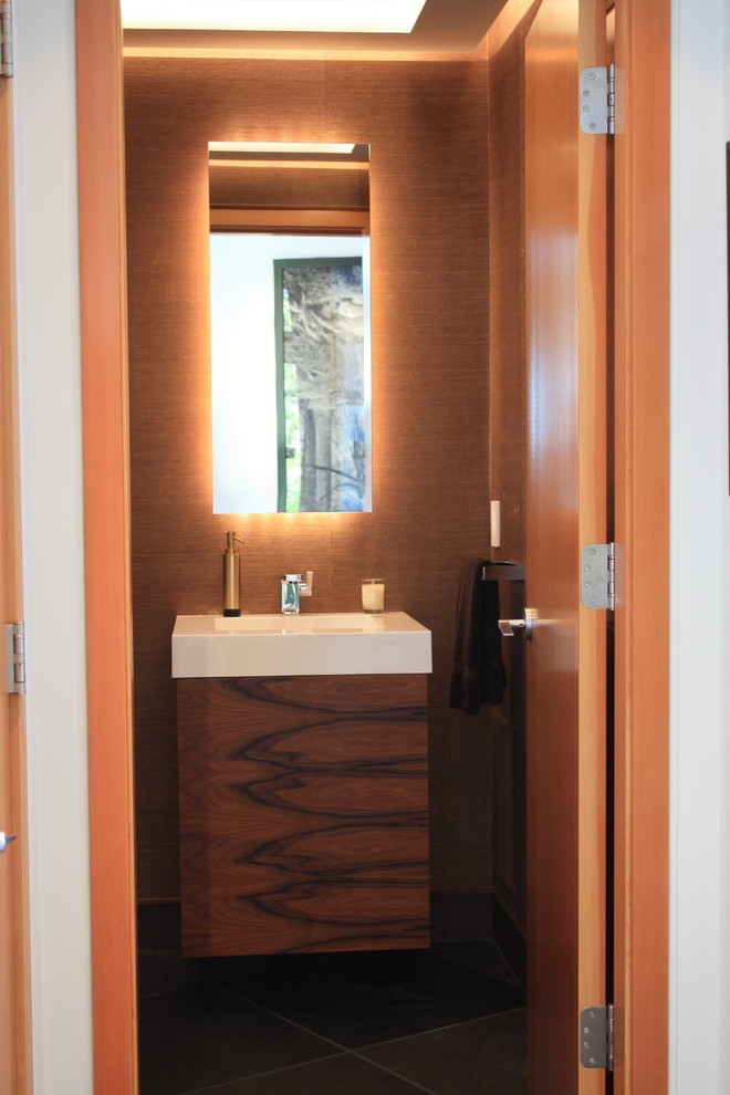 Immagine di un piccolo bagno di servizio design con ante lisce, ante in legno scuro, pareti marroni, lavabo integrato, pavimento nero e top bianco