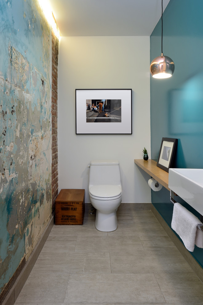 Cette photo montre un petit WC et toilettes moderne avec un mur bleu, un sol en carrelage de céramique, une vasque, un plan de toilette en bois, WC à poser, un sol gris et un plan de toilette marron.