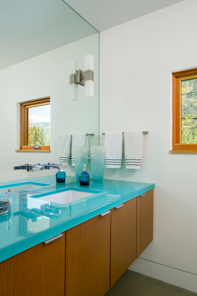 This is an example of a medium sized contemporary cloakroom in Denver with a submerged sink, flat-panel cabinets, medium wood cabinets, glass worktops, white walls and turquoise worktops.