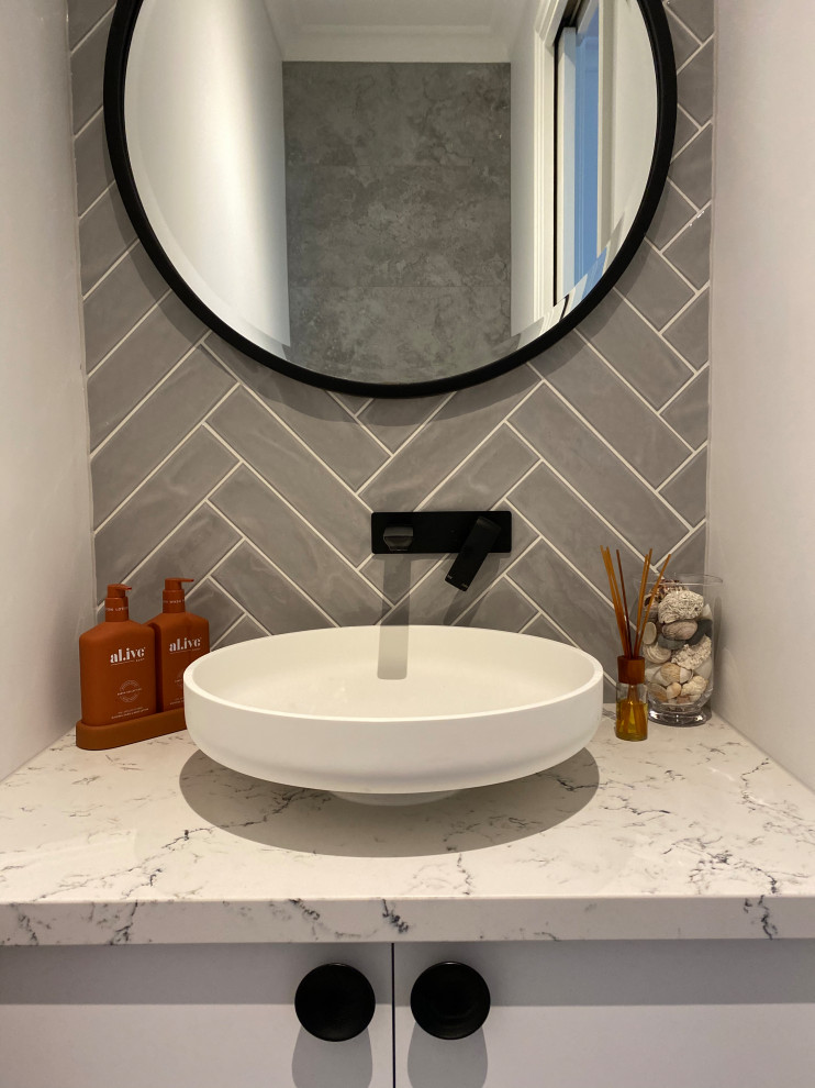 Small contemporary cloakroom in Melbourne with flat-panel cabinets, white cabinets, grey tiles, porcelain tiles, white walls, porcelain flooring, a vessel sink, engineered stone worktops and a built in vanity unit.