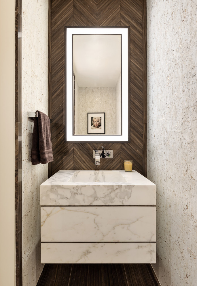 На фото: туалет в современном стиле с плоскими фасадами, белыми фасадами, коричневой плиткой, монолитной раковиной, коричневым полом, белой столешницей и акцентной стеной