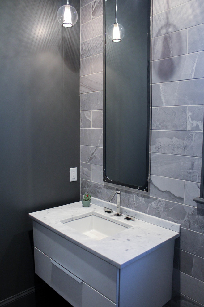 Inspiration för ett mellanstort funkis toalett, med släta luckor, vita skåp, grå kakel, stenkakel, grå väggar, mellanmörkt trägolv, ett undermonterad handfat och marmorbänkskiva