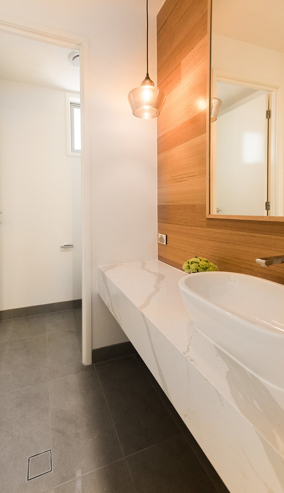 Idée de décoration pour un WC et toilettes design avec un carrelage blanc, un mur blanc, un sol en carrelage de porcelaine, une vasque, un plan de toilette en quartz modifié et un sol gris.