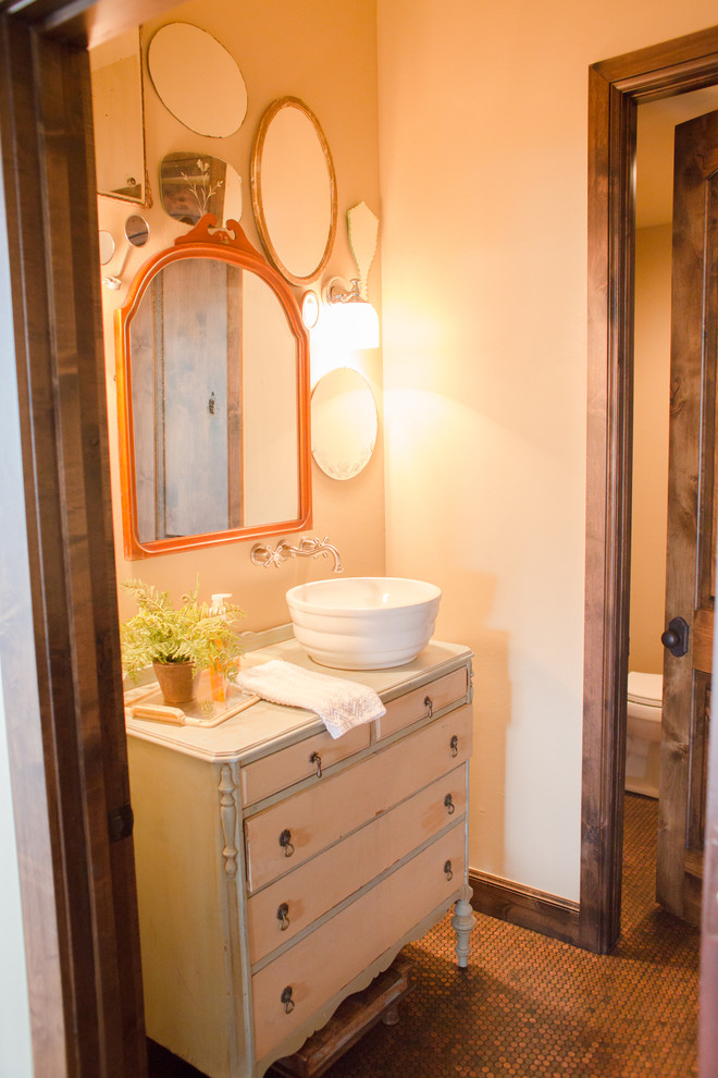 Cette image montre un petit WC et toilettes bohème en bois vieilli avec un placard à porte plane, un carrelage marron, WC séparés, un mur beige, un sol en carrelage de terre cuite et une vasque.