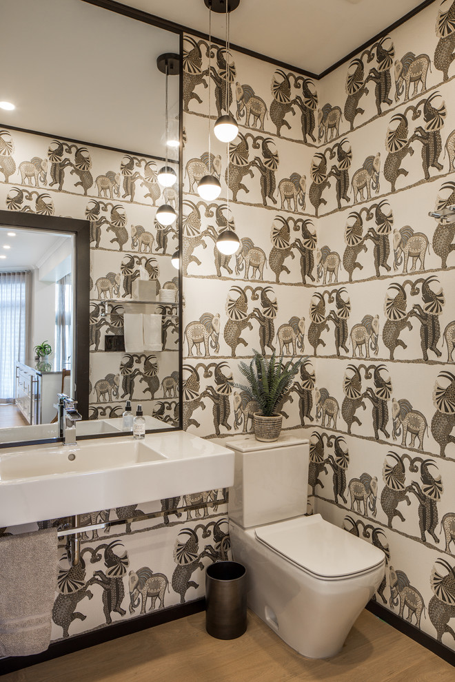バンクーバーにある高級な小さなトランジショナルスタイルのおしゃれなトイレ・洗面所 (分離型トイレ、淡色無垢フローリング、壁付け型シンク、ベージュの床、マルチカラーの壁) の写真