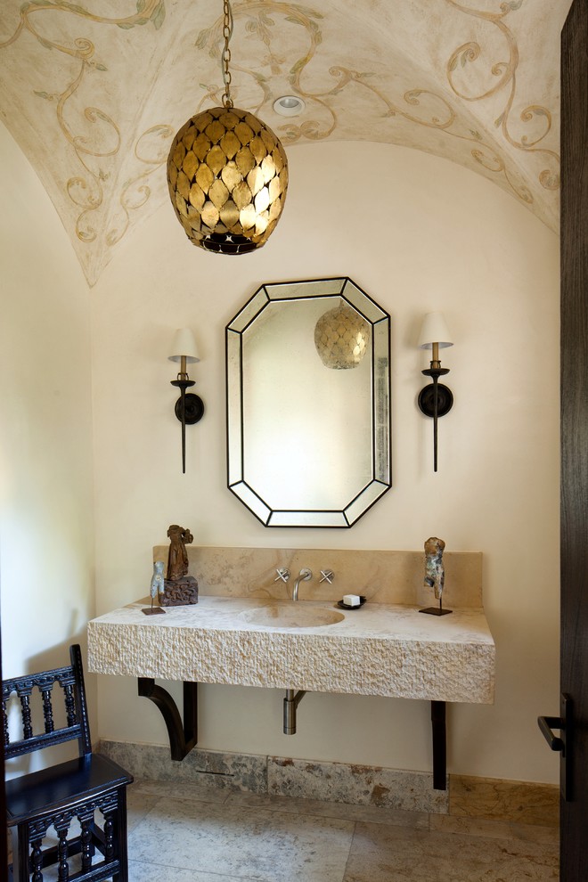 Medelhavsstil inredning av ett toalett, med kalkstensgolv, ett integrerad handfat och beige väggar