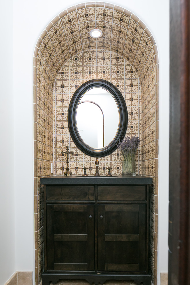 Example of a tuscan powder room design in Orange County with recessed-panel cabinets and dark wood cabinets