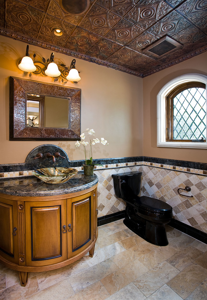 Foto på ett mellanstort medelhavsstil toalett, med travertinkakel, möbel-liknande, skåp i mellenmörkt trä, en toalettstol med separat cisternkåpa, bruna väggar, ett fristående handfat och granitbänkskiva