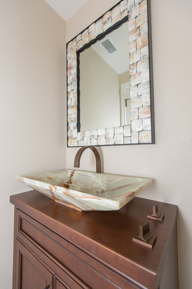 Cette image montre un petit WC et toilettes traditionnel en bois brun avec une vasque, un placard avec porte à panneau encastré, un plan de toilette en bois, WC séparés et un mur beige.