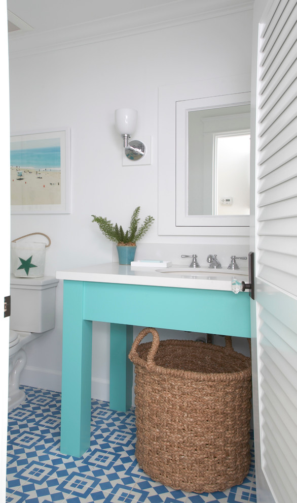 Inspiration for a medium sized beach style cloakroom in San Diego with a submerged sink, blue cabinets, engineered stone worktops, blue tiles, white walls, a two-piece toilet, cement flooring, multi-coloured floors and white worktops.