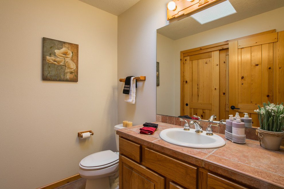 Exemple d'un WC et toilettes sud-ouest américain en bois clair de taille moyenne avec un placard à porte shaker, WC séparés, un carrelage multicolore, des carreaux de céramique, un mur blanc, un sol en carrelage de céramique, un lavabo posé et un plan de toilette en carrelage.