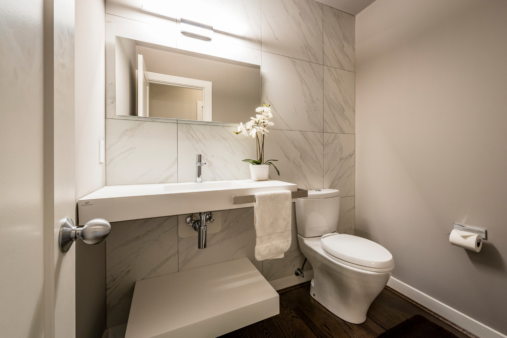 Idee per un bagno di servizio contemporaneo di medie dimensioni con WC a due pezzi, piastrelle grigie, pareti grigie, pavimento in legno massello medio, lavabo integrato e pavimento marrone