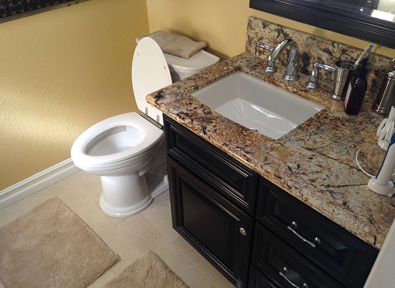 Cette photo montre un WC et toilettes tendance en bois foncé avec un placard en trompe-l'oeil, WC à poser, un mur beige, un sol en travertin, un lavabo encastré et un plan de toilette en marbre.