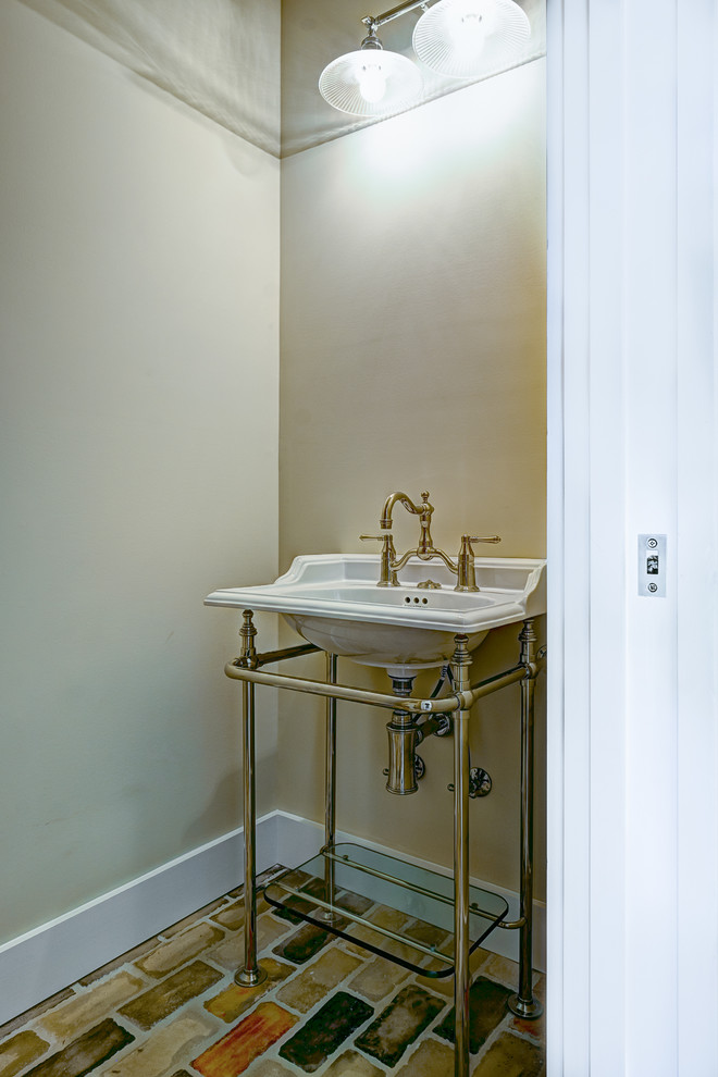 This is an example of a small industrial cloakroom in Miami with beige walls, brick flooring and a console sink.
