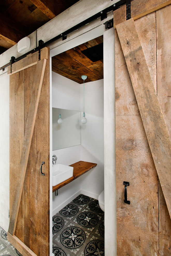 Industrial Gästetoilette mit Aufsatzwaschbecken, Waschtisch aus Holz, weißer Wandfarbe und brauner Waschtischplatte in Montreal