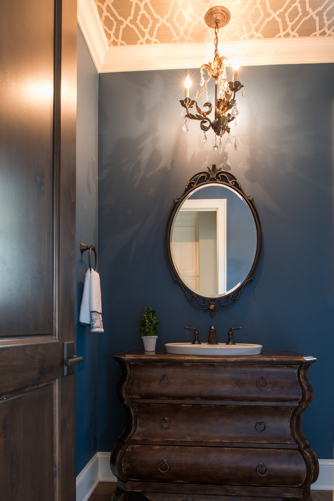 Exemple d'un WC et toilettes chic en bois foncé de taille moyenne avec un placard en trompe-l'oeil, un mur bleu, un sol en bois brun, une vasque, un plan de toilette en bois et un sol marron.