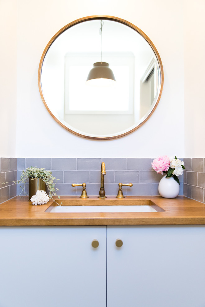 メルボルンにある小さなトランジショナルスタイルのおしゃれなトイレ・洗面所 (グレーのキャビネット、分離型トイレ、グレーのタイル、白い壁、磁器タイルの床、アンダーカウンター洗面器、木製洗面台) の写真