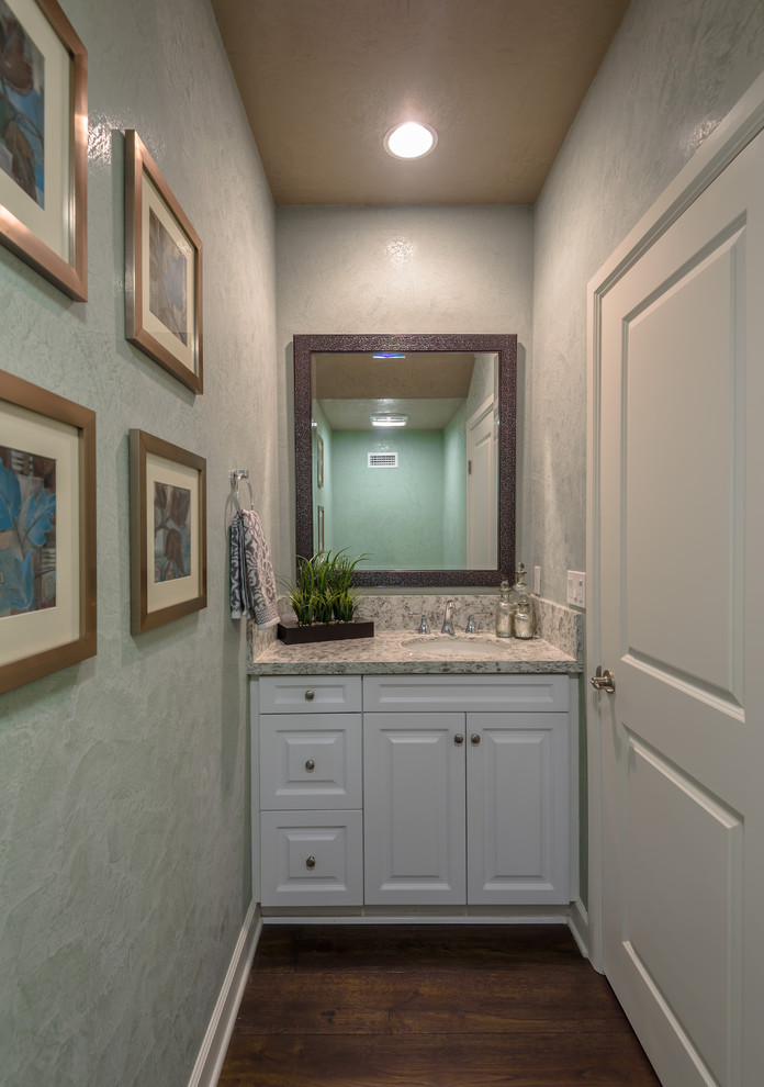 Mittelgroße Moderne Gästetoilette mit profilierten Schrankfronten, weißen Schränken, grüner Wandfarbe, dunklem Holzboden, Unterbauwaschbecken, Granit-Waschbecken/Waschtisch, Wandtoilette mit Spülkasten, braunem Boden und grauer Waschtischplatte in Orange County