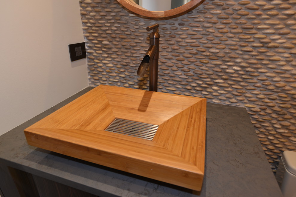 Diseño de aseo minimalista con puertas de armario de madera en tonos medios, suelo de baldosas tipo guijarro y lavabo con pedestal