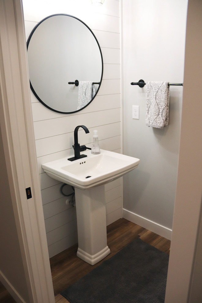 Small country cloakroom in Other with a two-piece toilet, multi-coloured walls, medium hardwood flooring, a pedestal sink and brown floors.