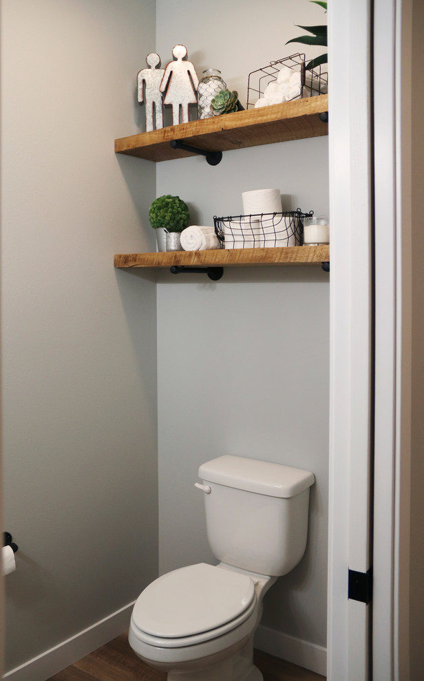Example of a small cottage medium tone wood floor and brown floor powder room design in Other with a two-piece toilet, multicolored walls and a pedestal sink