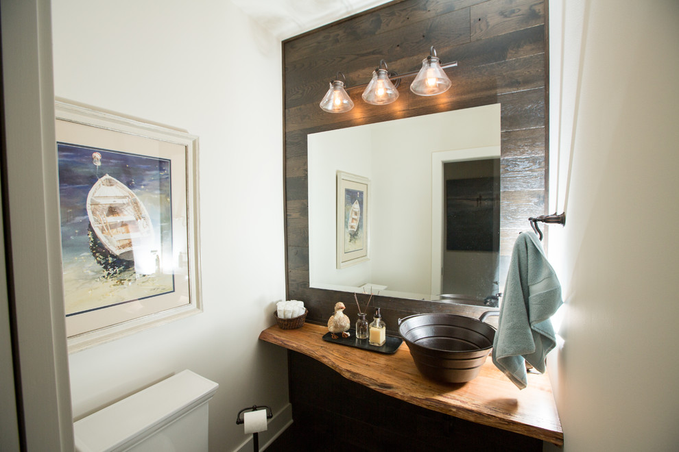 Example of a mid-sized transitional dark wood floor powder room design in Grand Rapids with open cabinets, distressed cabinets, a two-piece toilet, beige walls, a vessel sink and wood countertops