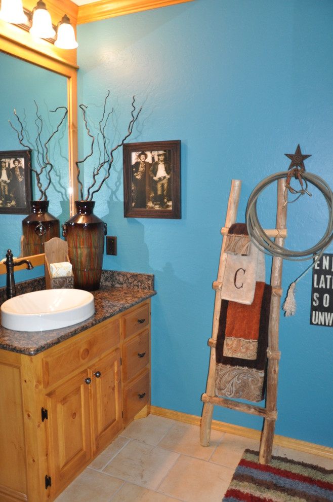 Idée de décoration pour un WC et toilettes tradition en bois clair de taille moyenne avec un lavabo posé, un placard avec porte à panneau surélevé, un plan de toilette en granite, un carrelage beige, un mur bleu, un sol en carrelage de céramique et un sol beige.