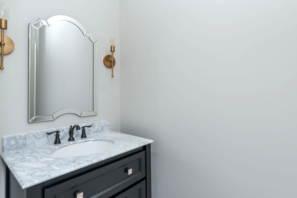 Example of a mid-sized transitional ceramic tile powder room design in Raleigh with furniture-like cabinets, black cabinets, a two-piece toilet, gray walls, an undermount sink and marble countertops