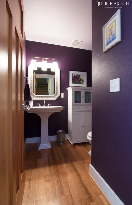 Imagen de aseo de estilo americano con lavabo con pedestal, puertas de armario blancas, sanitario de una pieza y paredes púrpuras