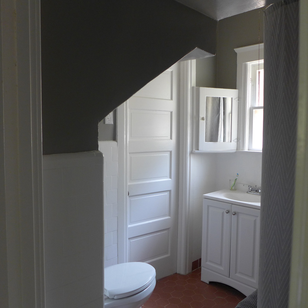 Réalisation d'un petit WC et toilettes craftsman avec un placard avec porte à panneau surélevé, des portes de placard blanches, un carrelage blanc, des carreaux de céramique, un mur gris et tomettes au sol.
