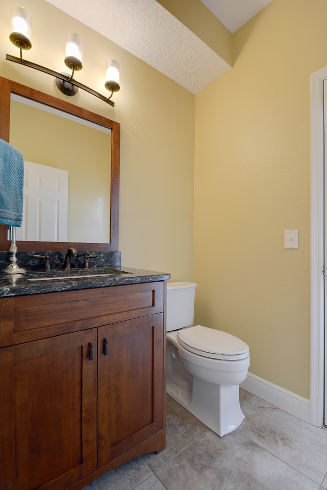 Aménagement d'un petit WC et toilettes craftsman en bois brun avec un lavabo encastré, un placard à porte shaker, un plan de toilette en quartz modifié, WC séparés, un mur beige et un sol en carrelage de porcelaine.
