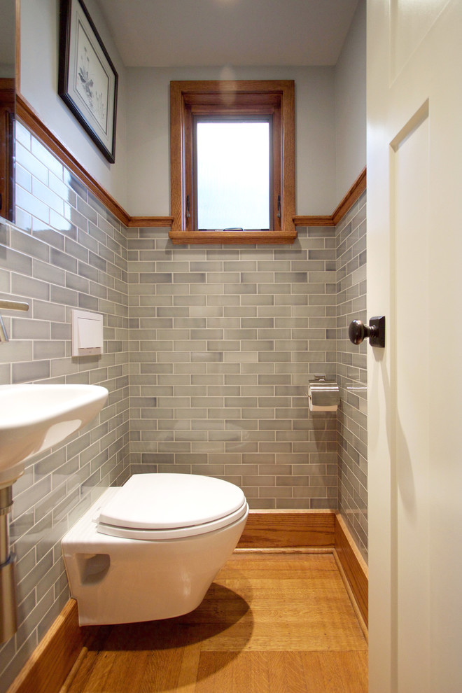 This is an example of a small traditional cloakroom in Other with a wall mounted toilet, grey tiles, metro tiles, grey walls, medium hardwood flooring and a wall-mounted sink.