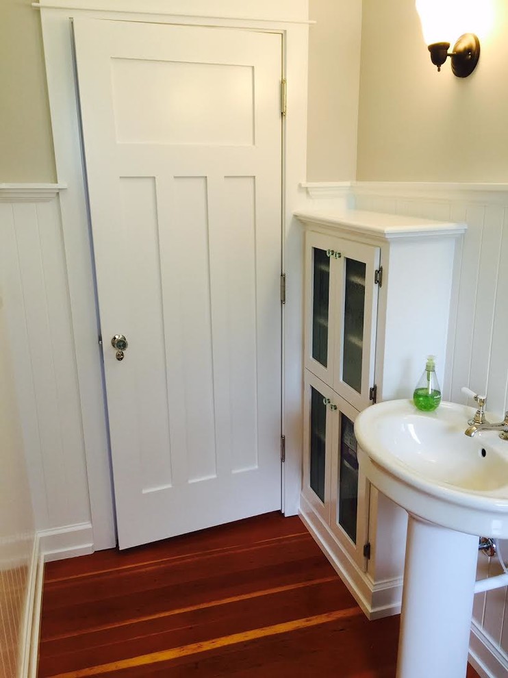 シアトルにある中くらいなトラディショナルスタイルのおしゃれなトイレ・洗面所 (ガラス扉のキャビネット、白いキャビネット、白い壁、濃色無垢フローリング、ペデスタルシンク) の写真