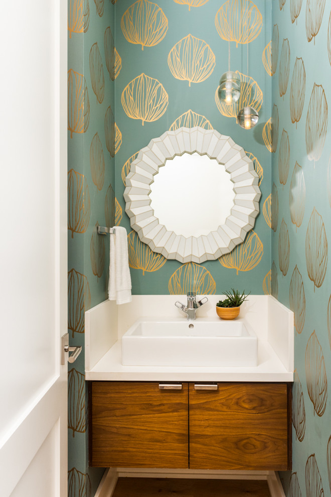 Foto på ett funkis vit toalett, med släta luckor, skåp i mellenmörkt trä, blå väggar, ett fristående handfat och brunt golv