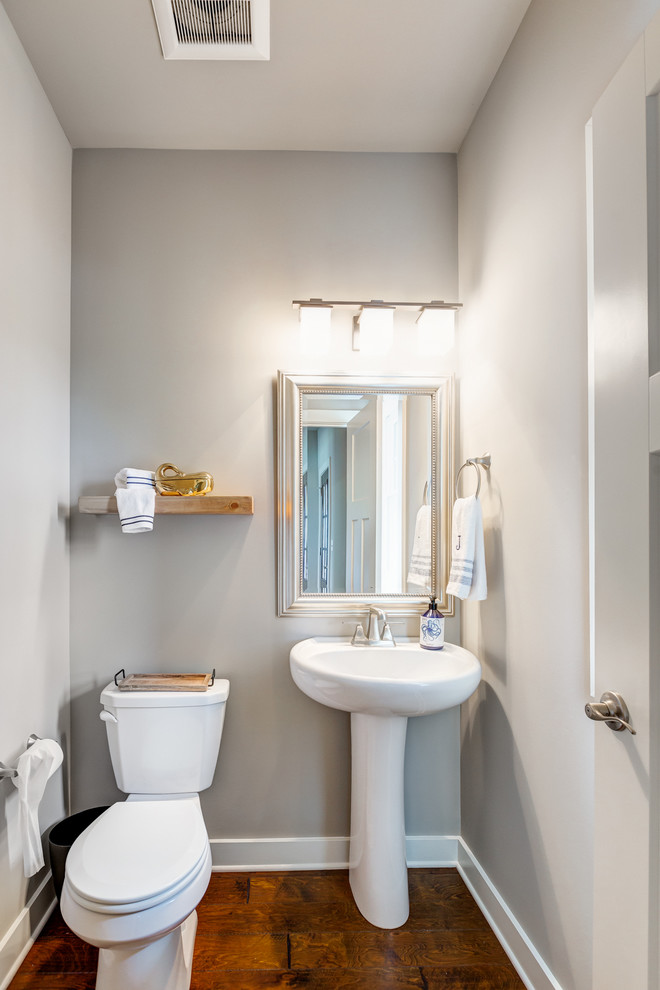 Foto di un bagno di servizio stile marino di medie dimensioni con WC monopezzo, pareti grigie, pavimento in legno massello medio e lavabo a colonna