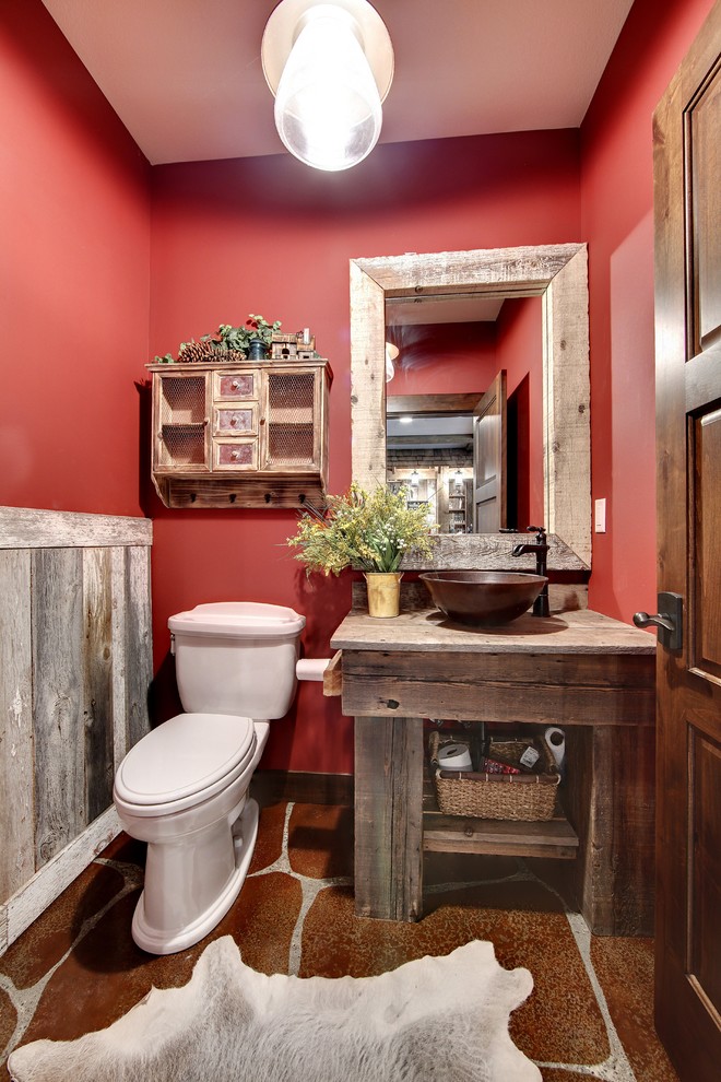 ミネアポリスにあるトラディショナルスタイルのおしゃれなトイレ・洗面所 (ヴィンテージ仕上げキャビネット、赤い壁、コンクリートの床、木製洗面台、赤い床) の写真