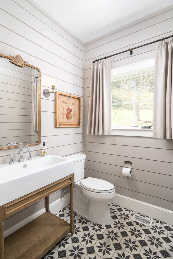 Landhaus Gästetoilette mit offenen Schränken, hellbraunen Holzschränken, Toilette mit Aufsatzspülkasten, grauer Wandfarbe, Waschtischkonsole und buntem Boden in Charlotte