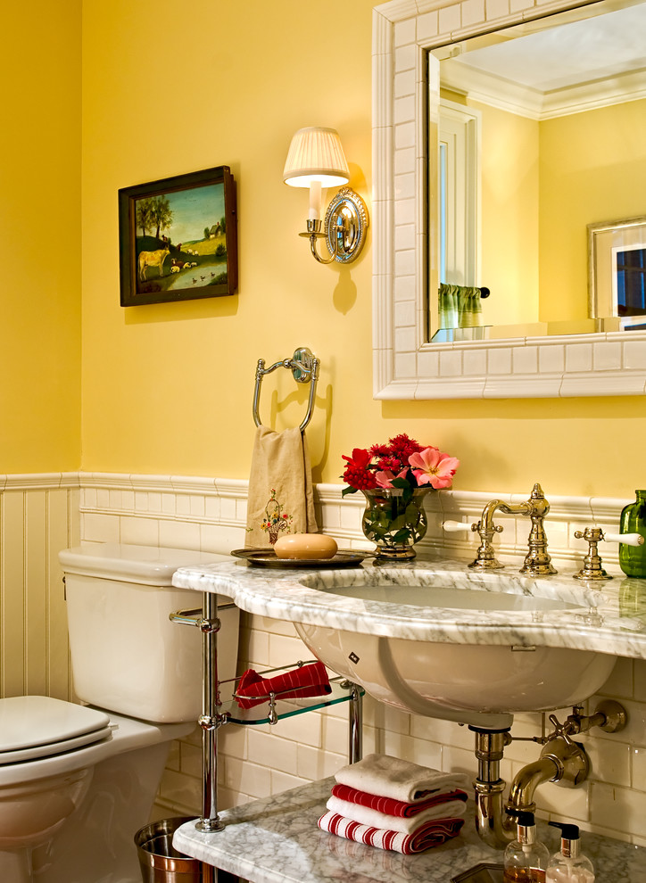 Пример оригинального дизайна: туалет в классическом стиле с мраморной столешницей, плиткой кабанчик, врезной раковиной, желтыми стенами и белой столешницей