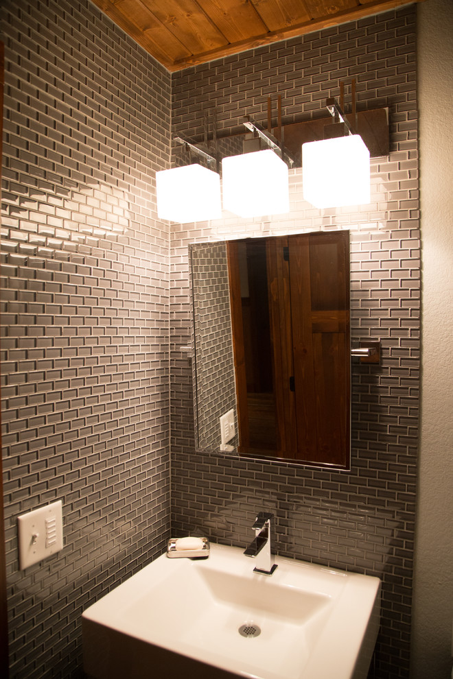 На фото: туалет в стиле модернизм с серой плиткой, раковиной с пьедесталом и стеклянной плиткой с