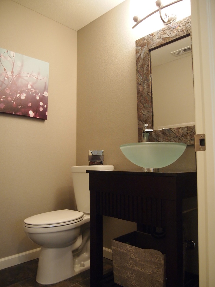 Modern inredning av ett litet toalett, med öppna hyllor, skåp i mörkt trä, beige väggar, skiffergolv, ett fristående handfat och träbänkskiva