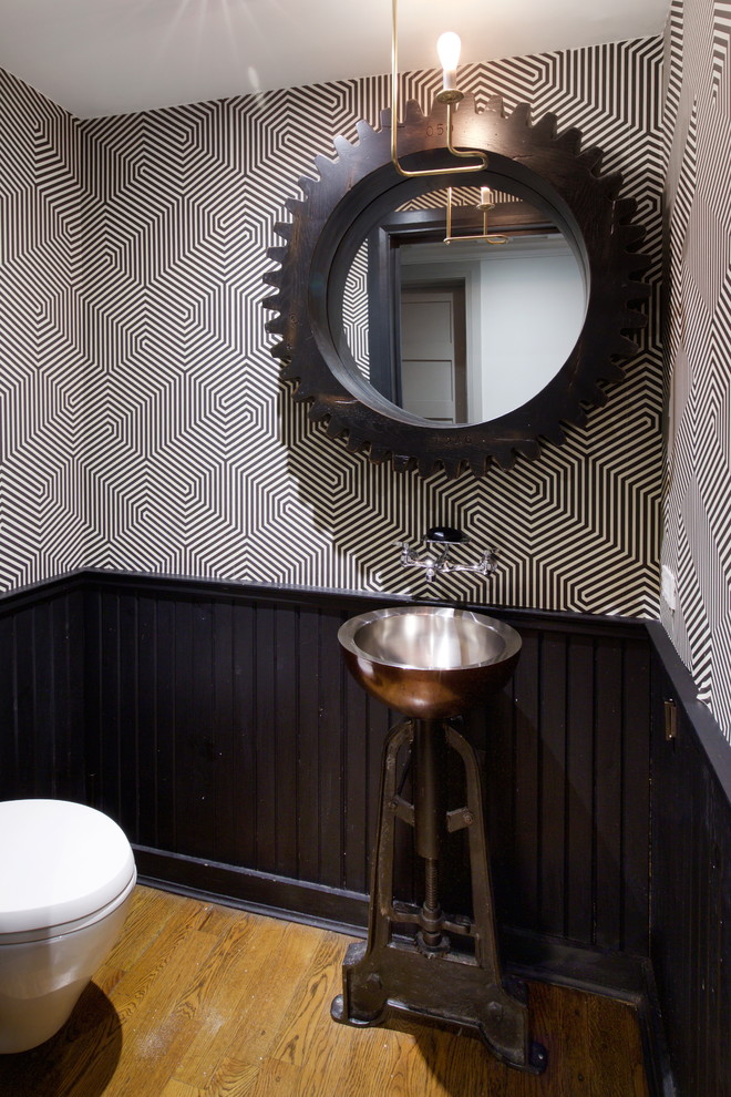 Immagine di un bagno di servizio tradizionale di medie dimensioni con WC sospeso, pareti nere, pavimento in legno massello medio, lavabo a colonna, top in acciaio inossidabile e pavimento marrone