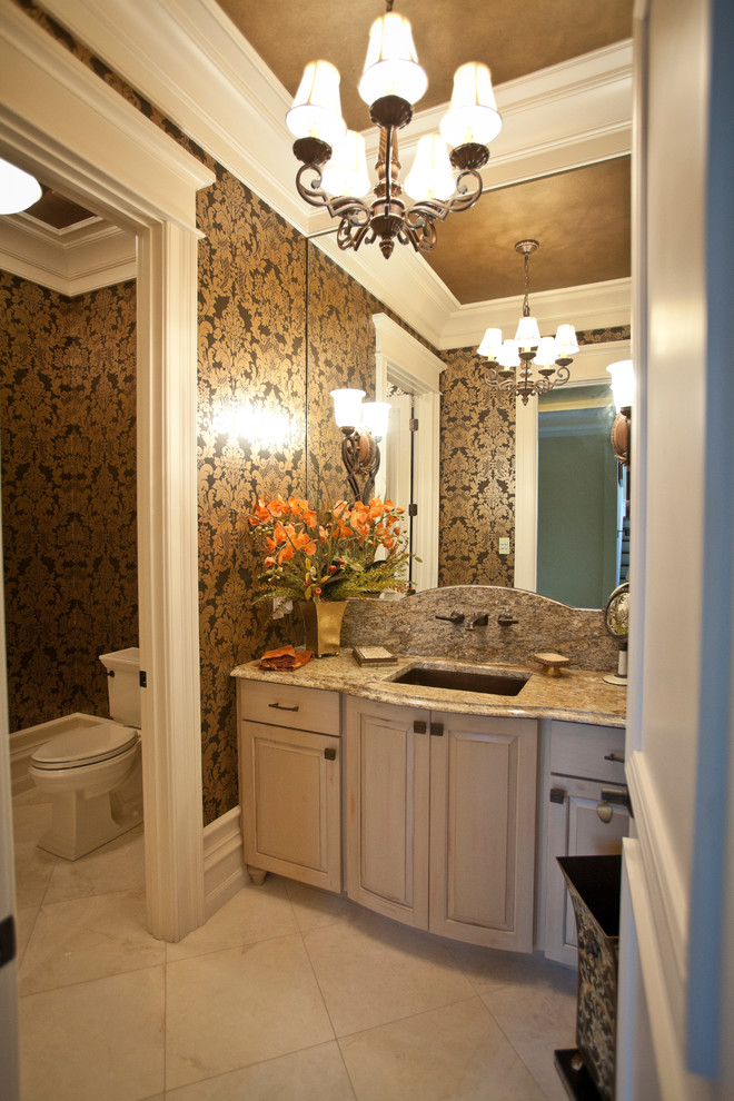 Immagine di un ampio bagno di servizio tradizionale con lavabo sottopiano, ante con bugna sagomata, top in granito, pavimento in marmo, WC a due pezzi e ante con finitura invecchiata