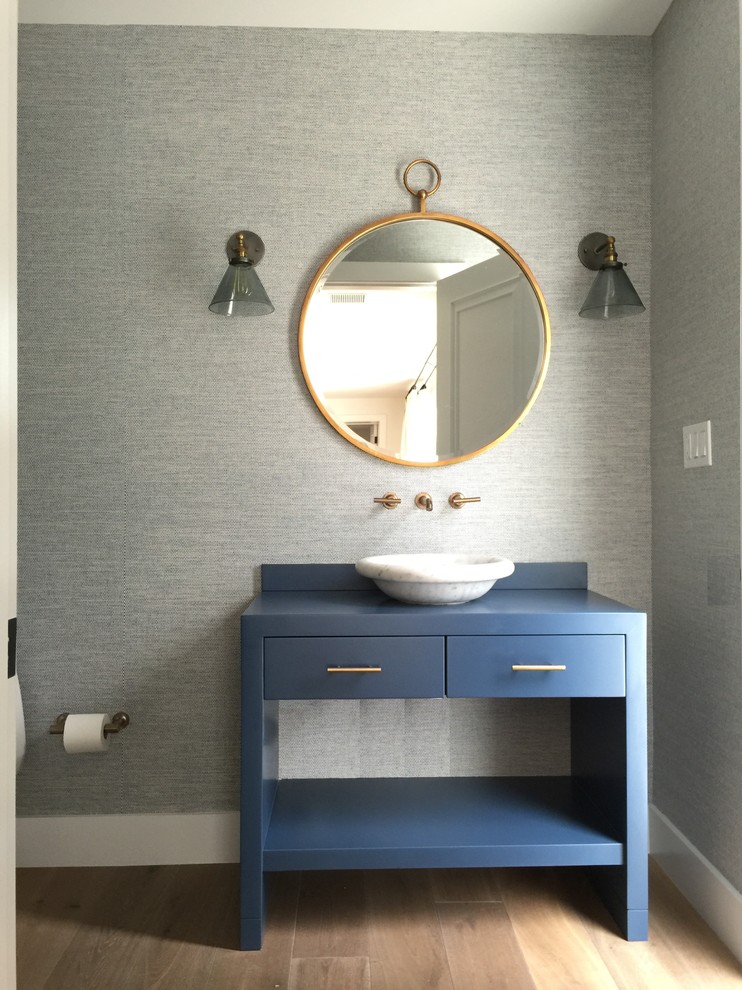 Cette photo montre un WC et toilettes chic de taille moyenne avec un placard en trompe-l'oeil, des portes de placard bleues, un mur gris, un sol en bois brun, une vasque, un plan de toilette en bois, un sol marron et un plan de toilette bleu.