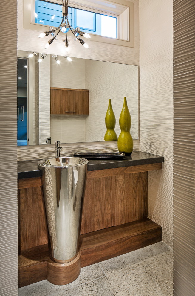 This is an example of a medium sized classic cloakroom in Omaha with freestanding cabinets, medium wood cabinets, beige tiles, beige walls, concrete flooring, a pedestal sink and quartz worktops.